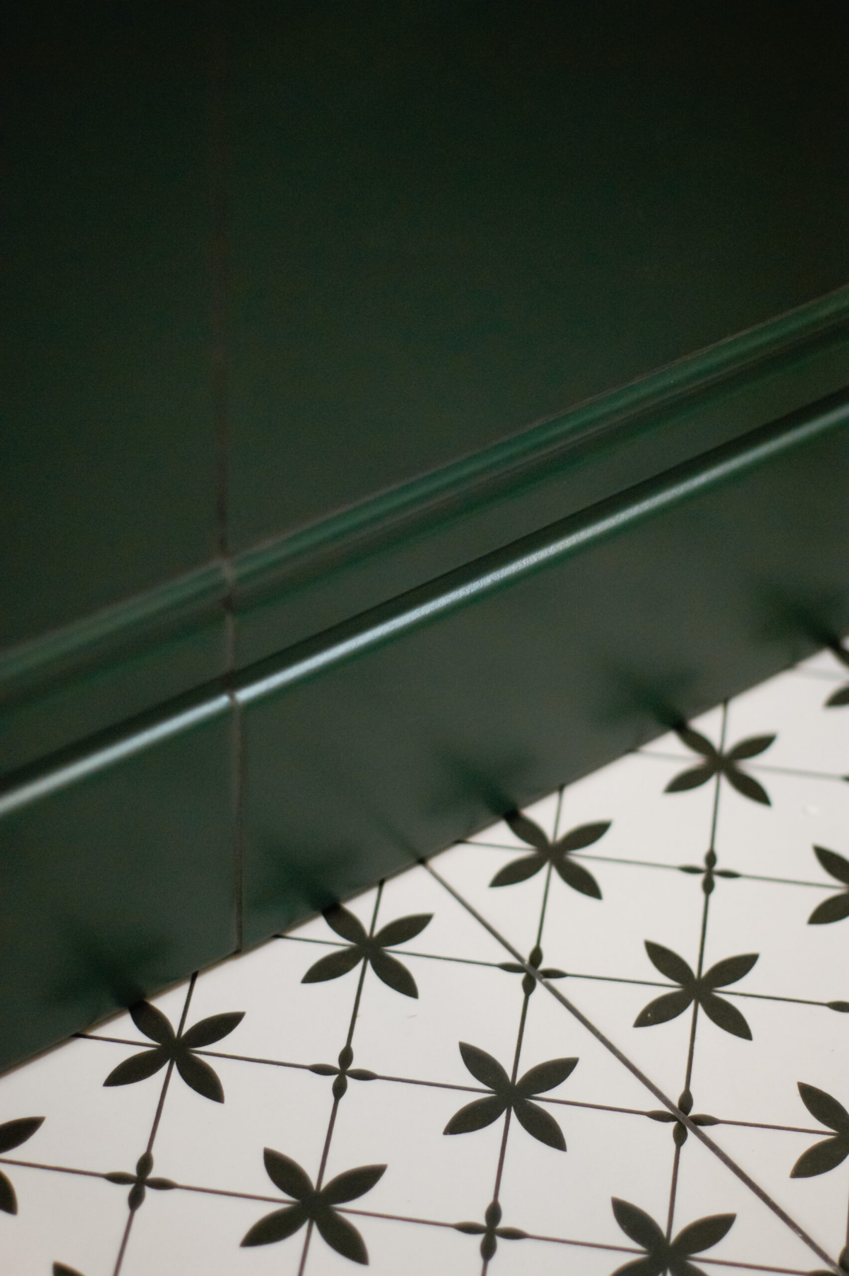 wzorzyste płytki ceramiczne na podłodze, zielona ściana w łazience